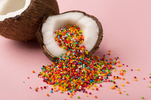 Mitades de coco con salpicaduras de azúcar en el interior en el fondo rosa
 - Foto, imagen