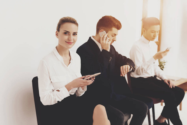 HR director woman in blouse and skirt sitting with coworkers and using smartphones - Фото, зображення