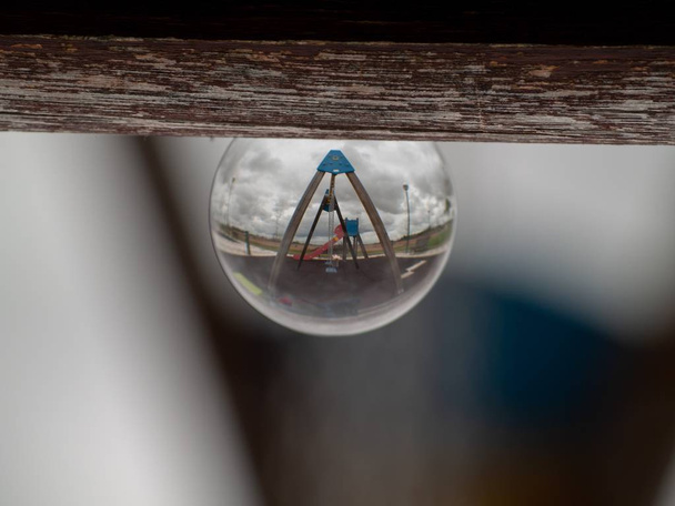 Reflexiones de columpios y toboganes en un parque en un concepto de bola de cristal / infancia
 - Foto, imagen