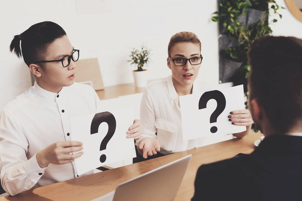 HR director woman in blouse and skirt working in office with coworker holding question marks at job interview  - Foto, Imagen