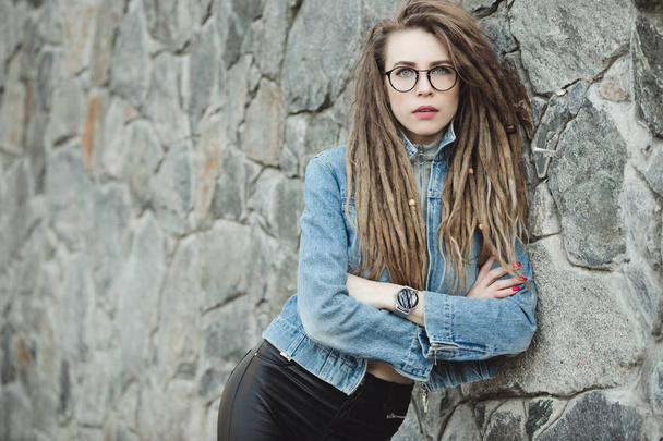 Pretty woman with dreadlocks standing at stones wall - Foto, Imagem