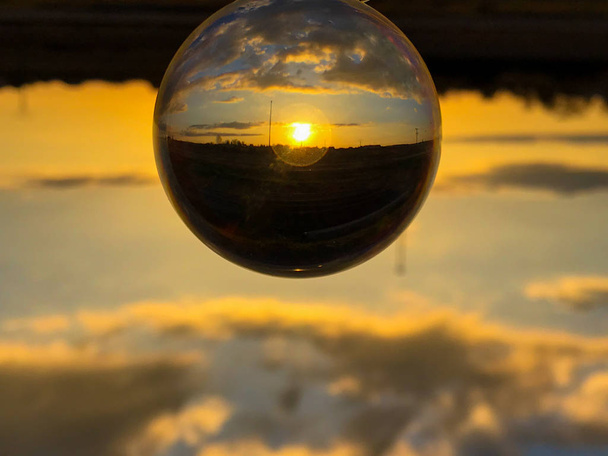 Reflejos de la puesta de sol en un día nublado en un concepto de bola de cristal / ambiente
 - Foto, imagen