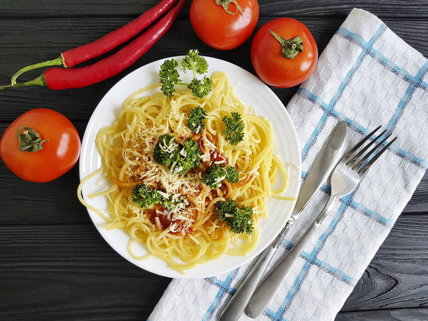spagetti lautasella, tomaattipersilja mustalla puupohjalla
 - Valokuva, kuva