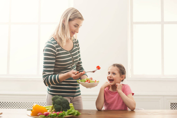 Beautiful woman offering her daughter salad - Photo, Image
