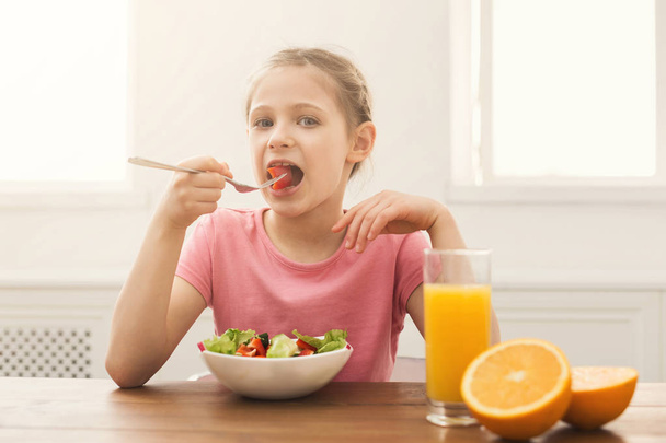 Child girl eating fresh salad and drinking orange juice - Фото, зображення