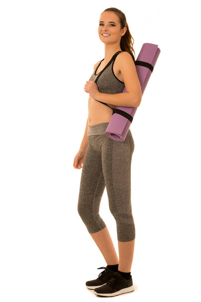 Beautiful young fit woman holds a mat ready for workout isolated - Fotografie, Obrázek