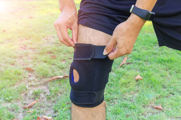 The man wear the Knee Support Brace Patella with sunlight in the park / Knee Pads Hole Sports - 写真・画像