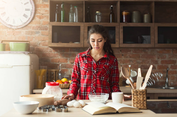 Serious young woman baking in loft kitchen - Foto, afbeelding