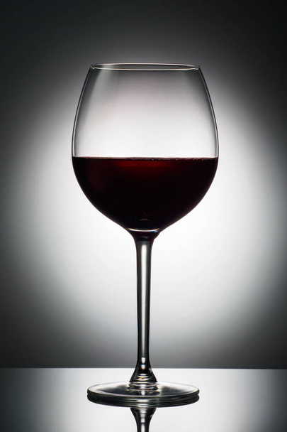 Large glass red wine shape of dark from grapes alcoholic beverage on luminous background advertising shot - Photo, Image