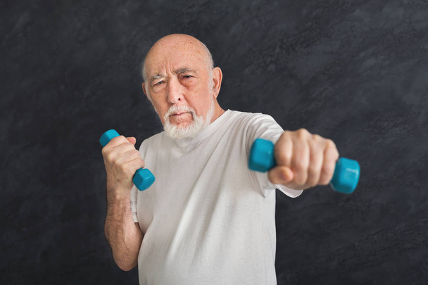 Vanhempi mies tekee liikuntaa käsipainoilla
 - Valokuva, kuva