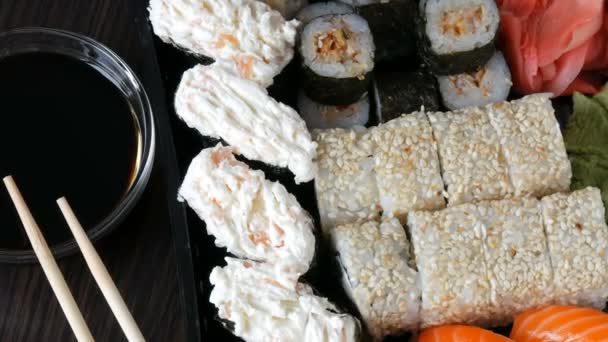 Iso sushi asetettu erilaisia sushi rullina, maki, nigiri, gunkan tyylikäs tumma tausta. Soijakastike ja bambu syömäpuikot sijaitsevat lähellä
 - Materiaali, video