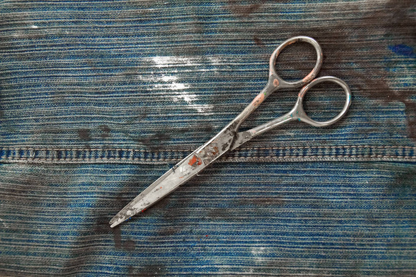 Old scissors, stained with oil paint over the durty jeans fabric - Photo, Image