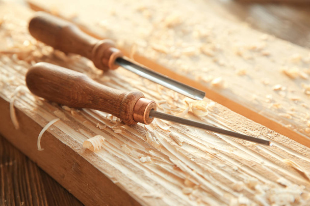 Chisels, wooden boards and sawdust in carpenter's workshop - Photo, Image