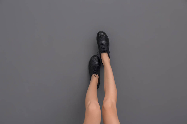 Legs of beautiful young woman in stylish shoes against gray background - Valokuva, kuva