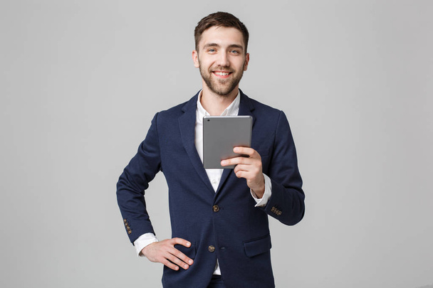 Geschäftskonzept - Porträt schöner Geschäftsmann spielt digitales Tablet mit lächelndem selbstbewusstem Gesicht. weißer Hintergrund. Kopierraum. - Foto, Bild