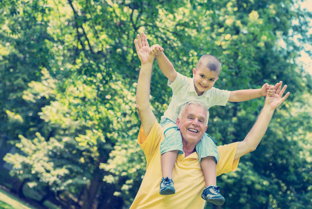 happy grandfather and child have fun and play in park on beautiful sunny day - Foto, immagini