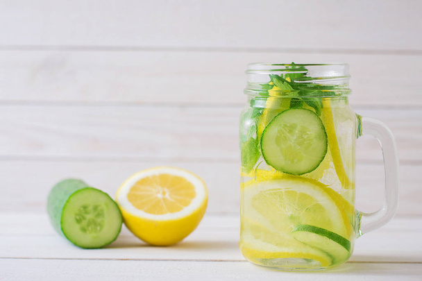 water met citroen en komkommer in een glazen beker - Foto, afbeelding