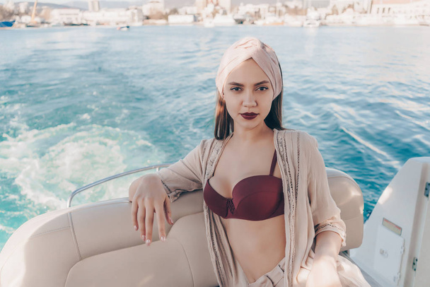 a luxurious young girl with a headscarf on her head swims on her white yacht on the Caribbean island on vacation - Φωτογραφία, εικόνα