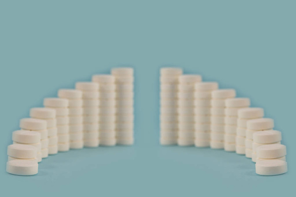 Reihe von Säulen aus weißen Tabletten, die in Form eines glatt gebogenen Bogens gesetzt sind. - Foto, Bild