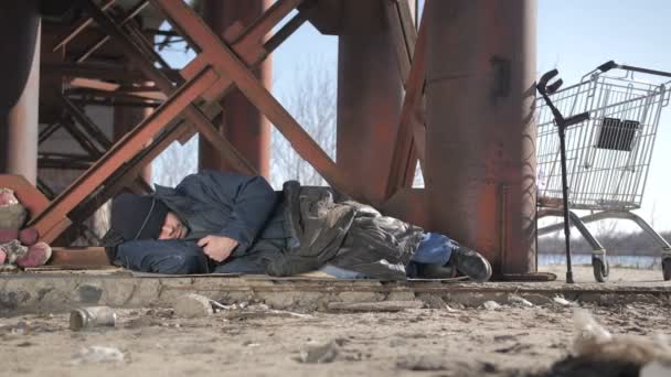 Frío mendigo sin hogar durmiendo bajo el puente
 - Imágenes, Vídeo