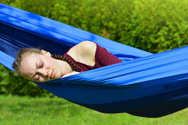 Fiatal gyönyörű nő alszik hintaágy a kertben. - Fotó, kép