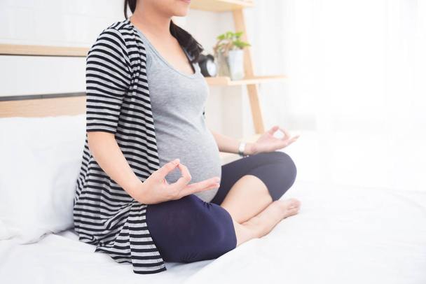 Азіатський вагітна робити медитація йога на ліжку - Фото, зображення