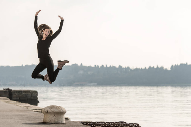 Giovane donna che salta per la gioia sopra un dissuasore
 - Foto, immagini
