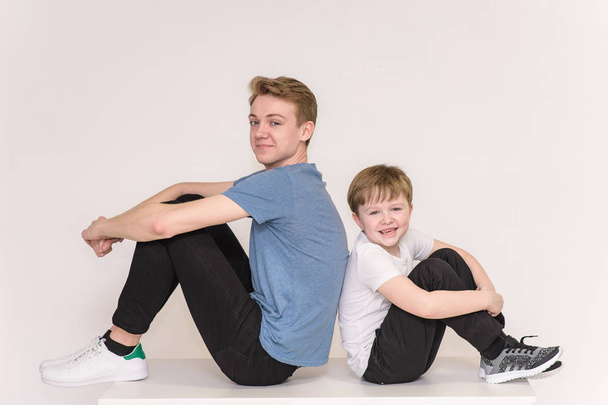 young man and boy 6 years old on a white background showing different emotions in different poses - Zdjęcie, obraz