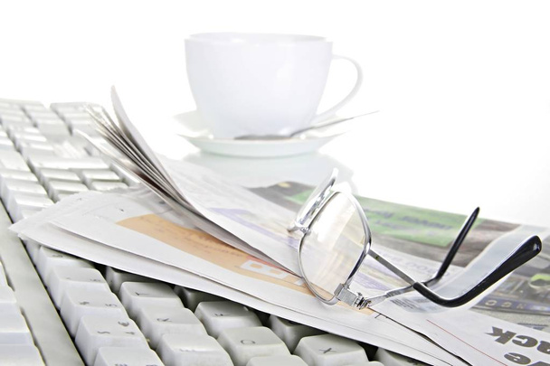 krant en bril met toetsenbord op een tafel - Foto, afbeelding