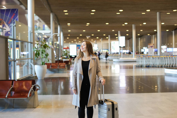Европейская женщина в сером пальто ходит по коридору аэропорта
. - Фото, изображение