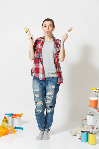 Full length portrait of fun cute woman with brush standing near instruments for renovation apartment home isolated on white background. Wallpaper accessories for gluing painting tools. Repair concept. - Photo, Image