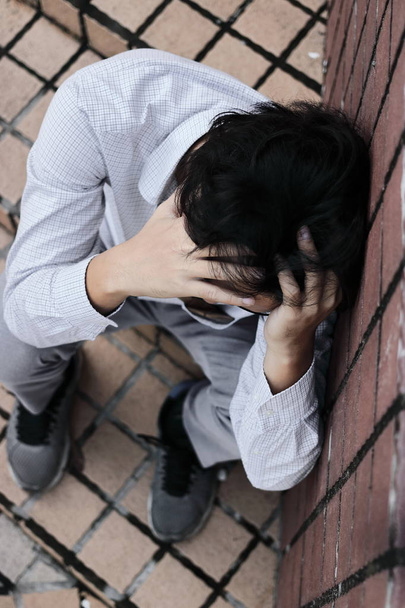 Vista aérea de ansioso estresado joven asiático hombre de negocios tocando la cara con las manos y llorar
. - Foto, Imagen