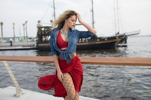 Beautiful woman in a red dress on a ship background. - Fotó, kép