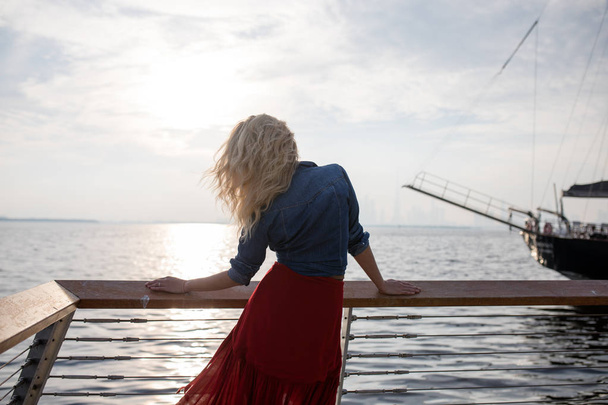 Beautiful woman in red dress on the background of the sea. - Photo, Image
