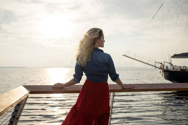 Beautiful woman in red dress on the background of the sea. - Фото, зображення