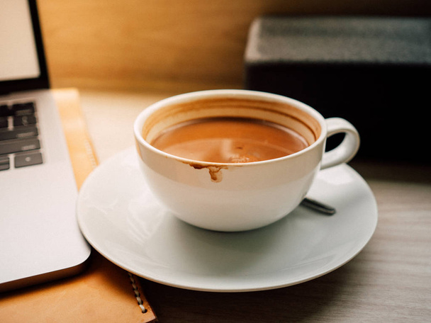 Laptop und eine Tasse Kaffee mit Morgenlicht im Café. - Foto, Bild
