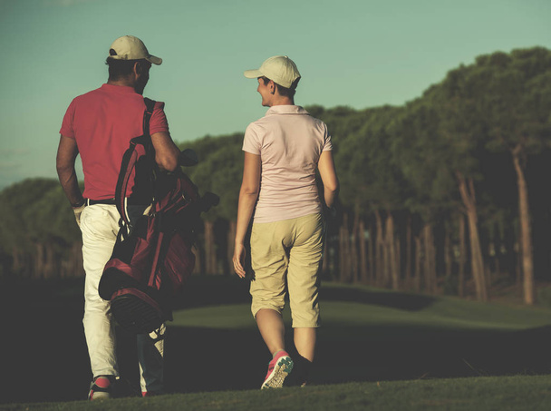 young couple walking to next hole on golf course - Fotoğraf, Görsel
