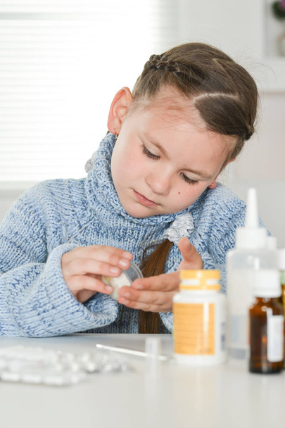 young sick girl taking  medicines while sitting at table - Foto, imagen