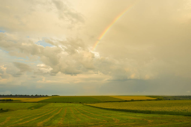 The vast expanse of different fields and the rainbow in the sky after the rain. Magnificent landscape. - Photo, image