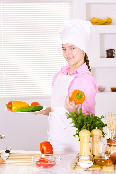 beautiful  girl wearing chef uniform with vegetables  on kitchen  - Foto, Imagem