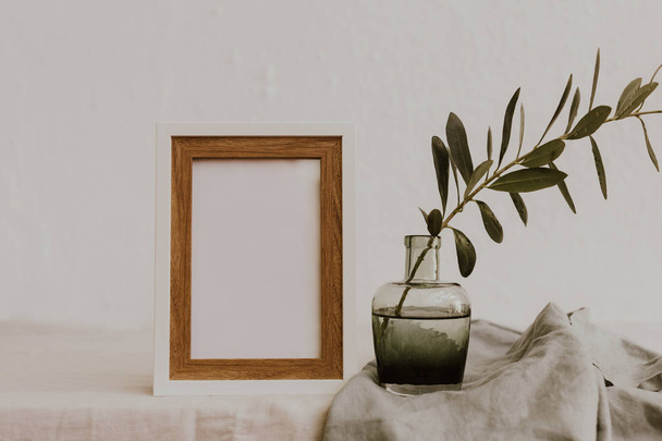 Mock up with olive branch in vase over linen tablecloth. Minimal eco concept  - Fotó, kép