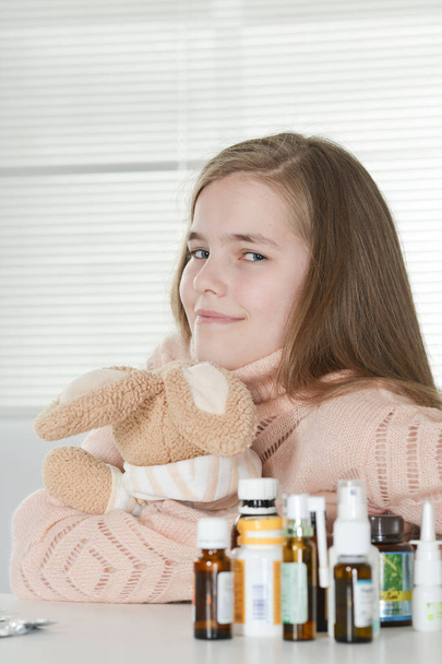 young sick girl with toy and medicines sitting at table - Photo, Image