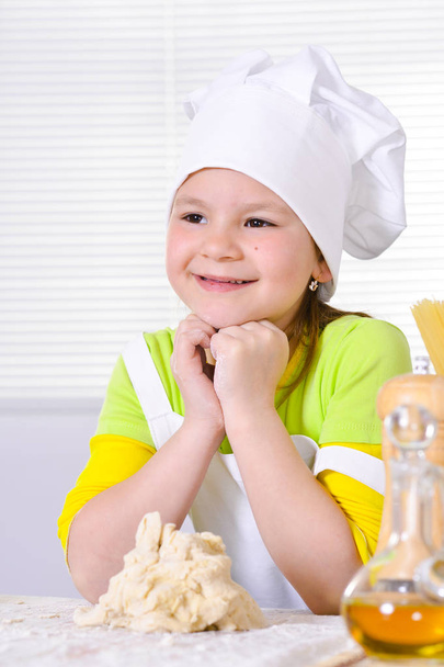Cute little girl in chef's hat baking cake in the kitchen at home - Fotografie, Obrázek