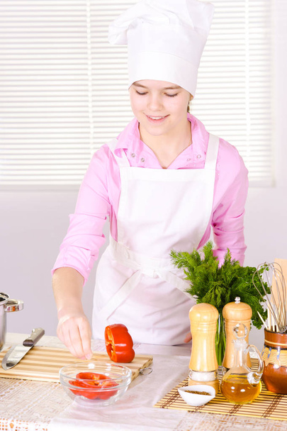 beautiful  girl wearing chef uniform with vegetables  on kitchen  - Foto, Imagen