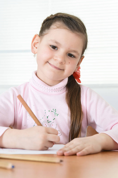 Cute schoolgirl sitting at table and drawing  at home - Фото, изображение