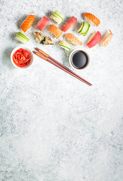 Zestaw na białym tle betonowych różne sushi. Miejsca na tekst. Japońskie sushi, rolki, sos sojowy, imbir, pałeczki. Widok z góry. Sushi nigiri. Japoński obiad. Rama żywności. Różnych sushi mieszane - Zdjęcie, obraz