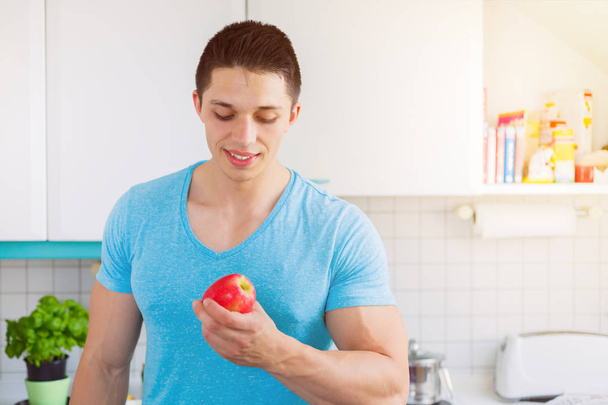 Healthy eating young man eat apple fruit in the kitchen copyspac - Фото, изображение
