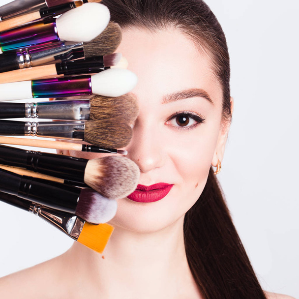 The face of a beautiful girl and make-up brush on white backgrou - Valokuva, kuva
