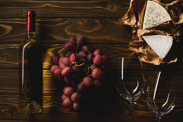 vista superior de botella de vino blanco con copas, uvas y queso sobre mesa de madera
 - Foto, Imagen