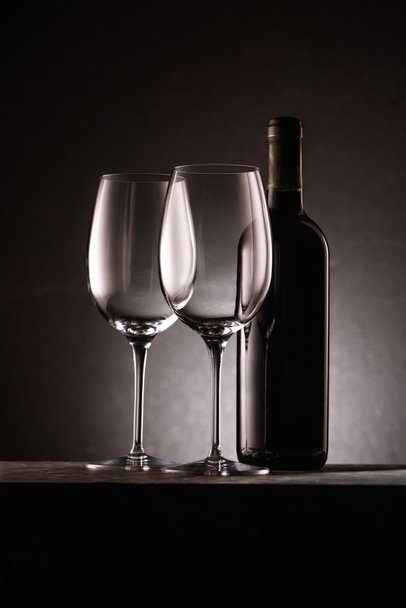 пляшка вина з двома порожніми келихами на чорному
 - Фото, зображення